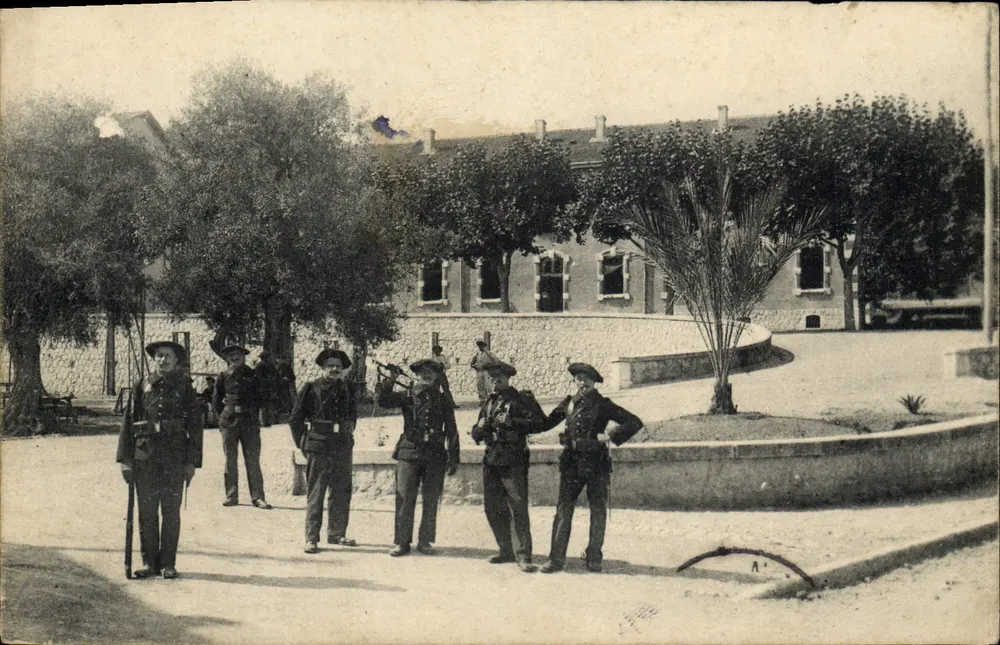 Cinq soldats en uniforme — cour d'un bâtiment avec palmier — éditeur non visible - Frente