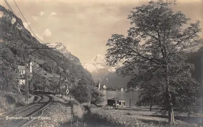Gotthardbahn bei Flüelen — vue de la ligne ferroviaire au bord du lac, avec église et montagnes en arrière-plan — éditeur Kunstverlag E. Goetz, Luzern, n° 1779