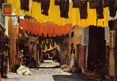 Marché des teinturiers à Marrakech — rue ombragée par des tissus colorés — éditeur Komaroc SA
