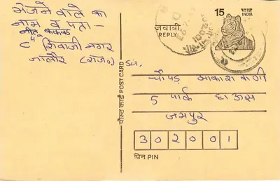Carta postal indiana — texto em escrita devanagari — selo de 15 roupias com tigre — destinatário em Jaipur — Verso