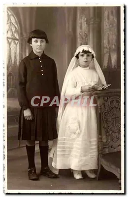 Two young girls — one in a communion dress — in front of cathedral décor