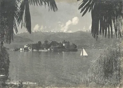 Lago Maggiore: ISOLA BELLA — visão tirada de um quadro de palmeiras, com montanhas nevadas e um barco à distância