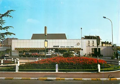 Estação SNCF de Aulnay-sous-Bois — vista da entrada com estacionamento e flores — edição LYNACOLOR