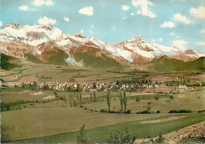 Vila em vale — montanhas nevadas no fundo — editor não identificável
