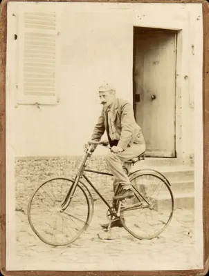 Homem de bicicleta — diante de uma porta e uma janela com persianas —