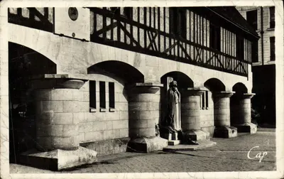 Santa Joana d'Arc — estátua diante de um edifício com madeira e arcos — Cap